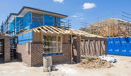 Double-storey homes at lock-up stage with brickwork and wrapped frames